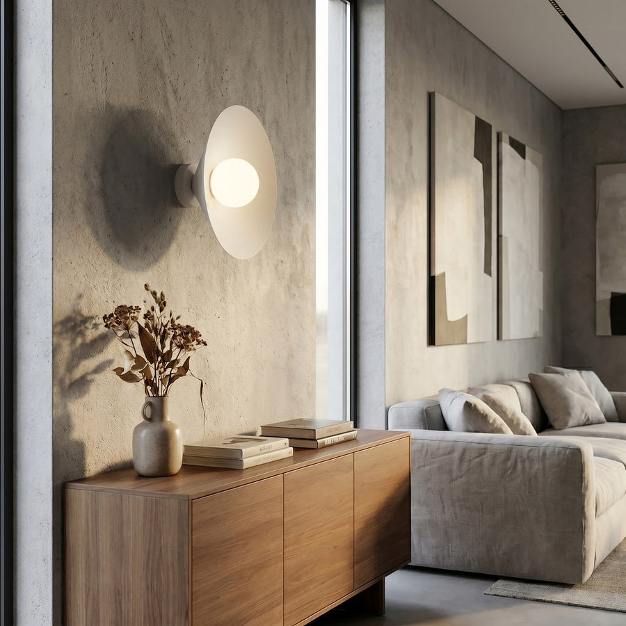 Mise en ambiance dans un salon, applique allumée au-dessus d'un meuble en bois