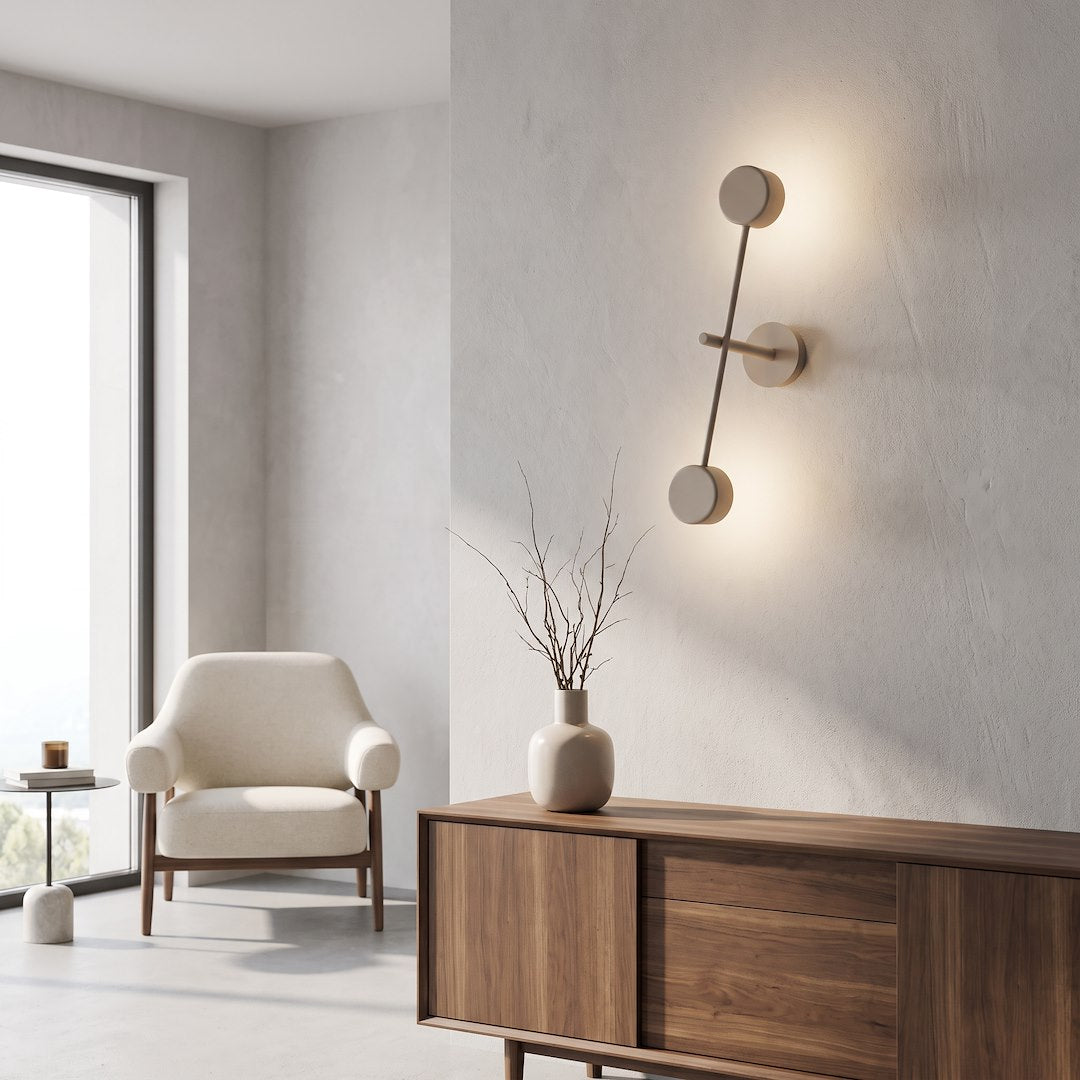 Mise en ambiance dans un salon moderne, applique murale beige allumée au-dessus d'un meuble.