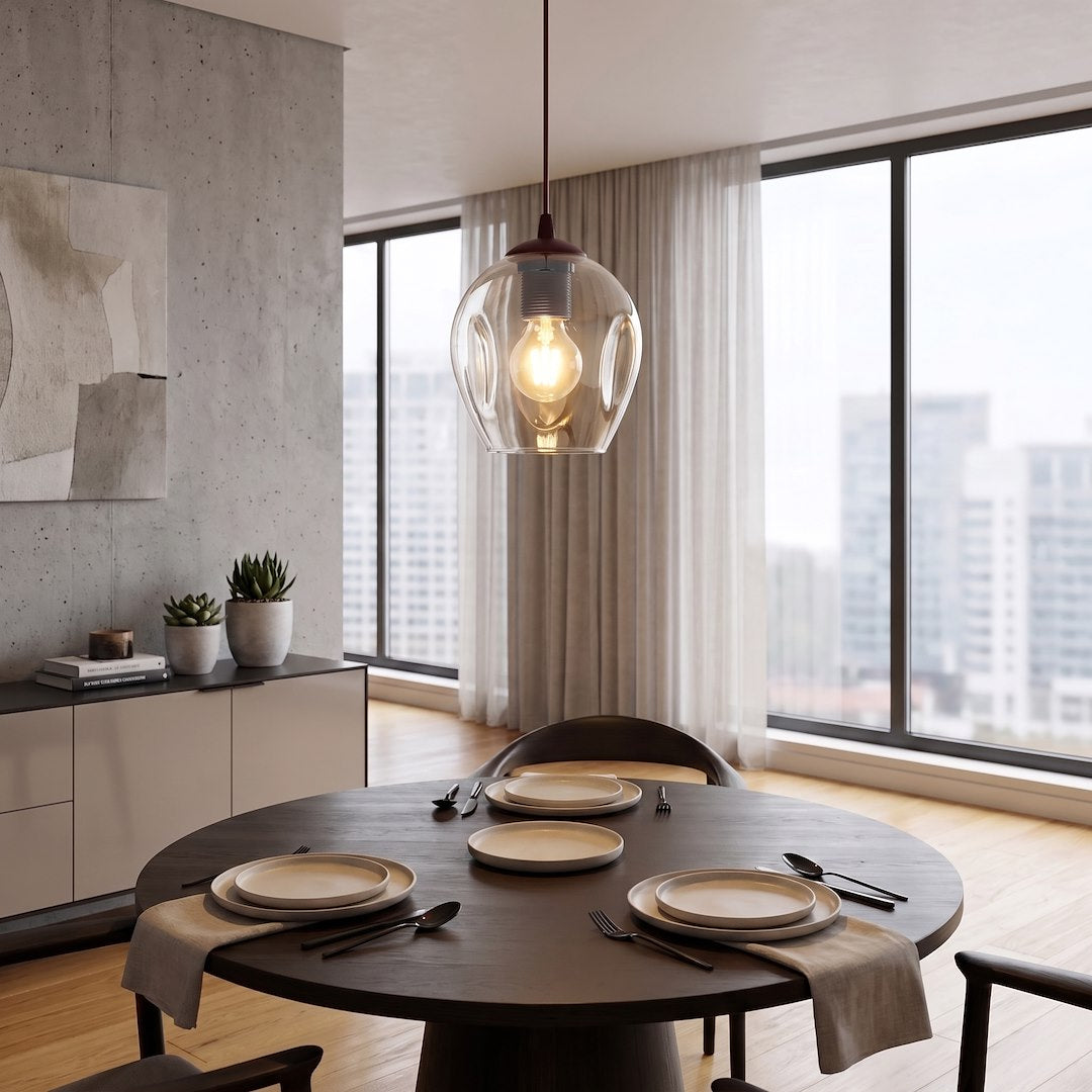 Suspension allumée au-dessus d'une table ronde, intérieur béton et grandes baies vitrées
