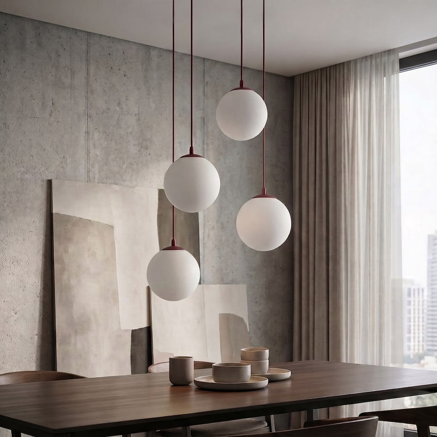 Suspension allumée au-dessus d'une table dans un séjour béton, quatre globes blancs