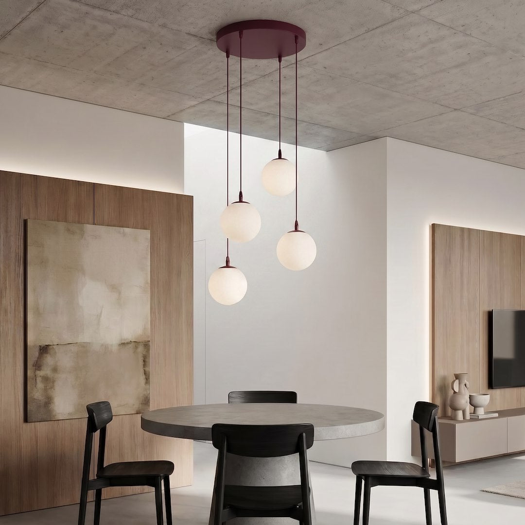 Luminaire suspendu au-dessus d'une table ronde entourée de chaises noires, intérieur contemporain