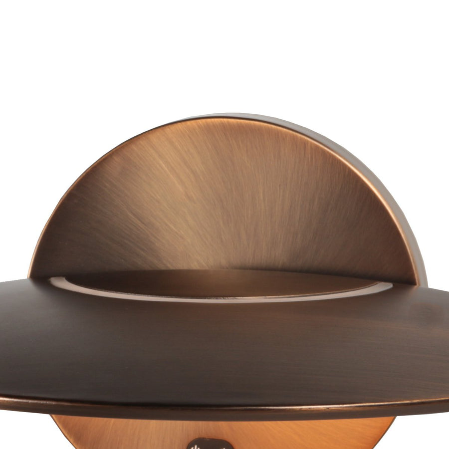 Gros plan sur le support semicirculaire bronze brossé et la fente lumineuse du disque.