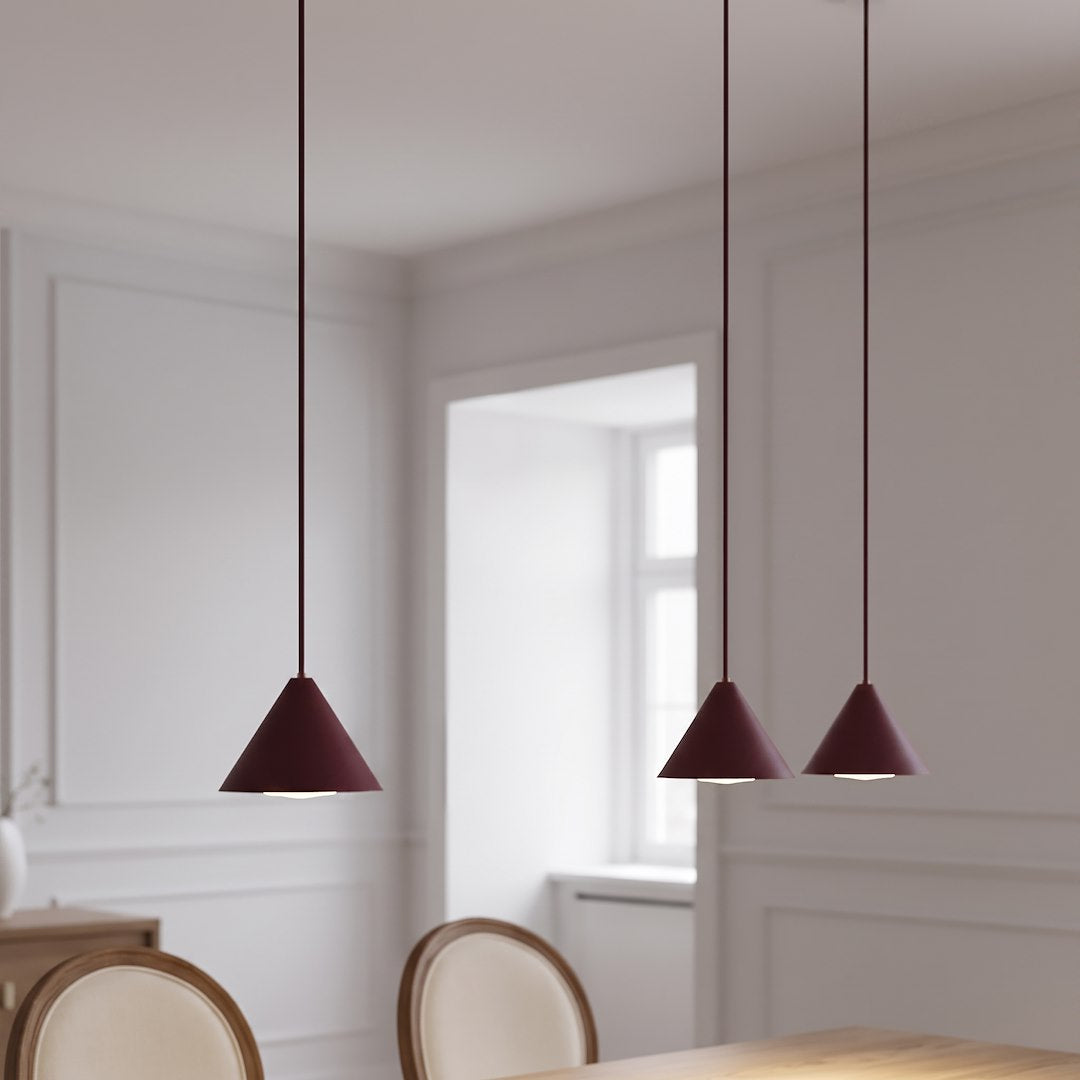 Mise en ambiance au-dessus d'une table de salle à manger, suspension bordeaux allumée.