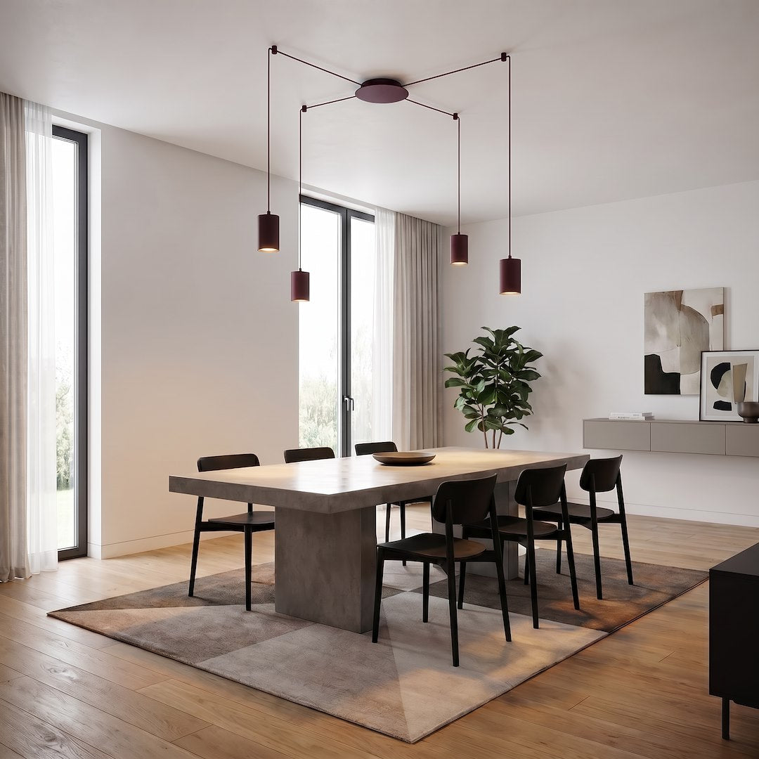 Mise en ambiance dans une salle à manger moderne, suspension allumée au-dessus de la table.
