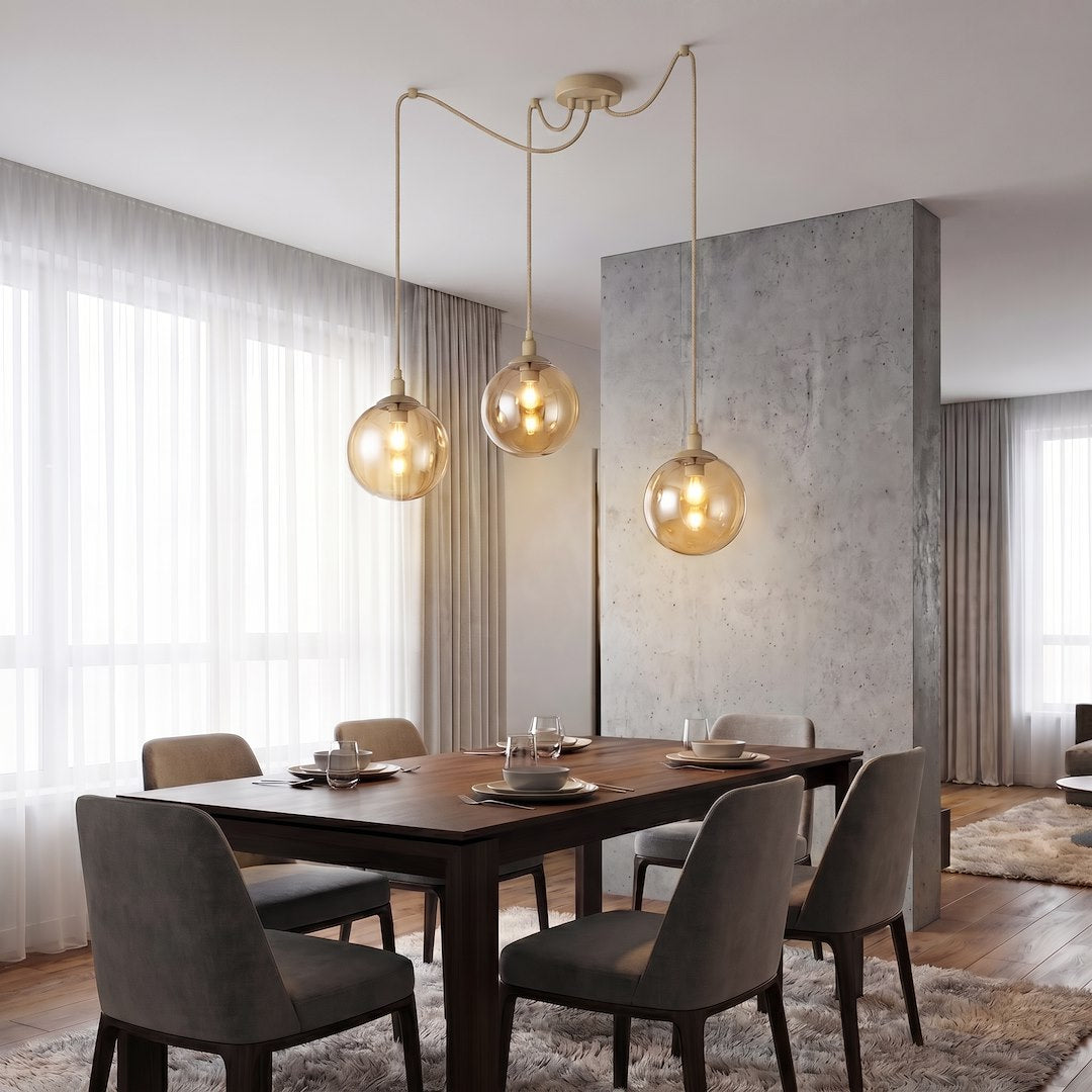 Mise en ambiance salle à manger, trois globes ambrés suspendus au-dessus de la table