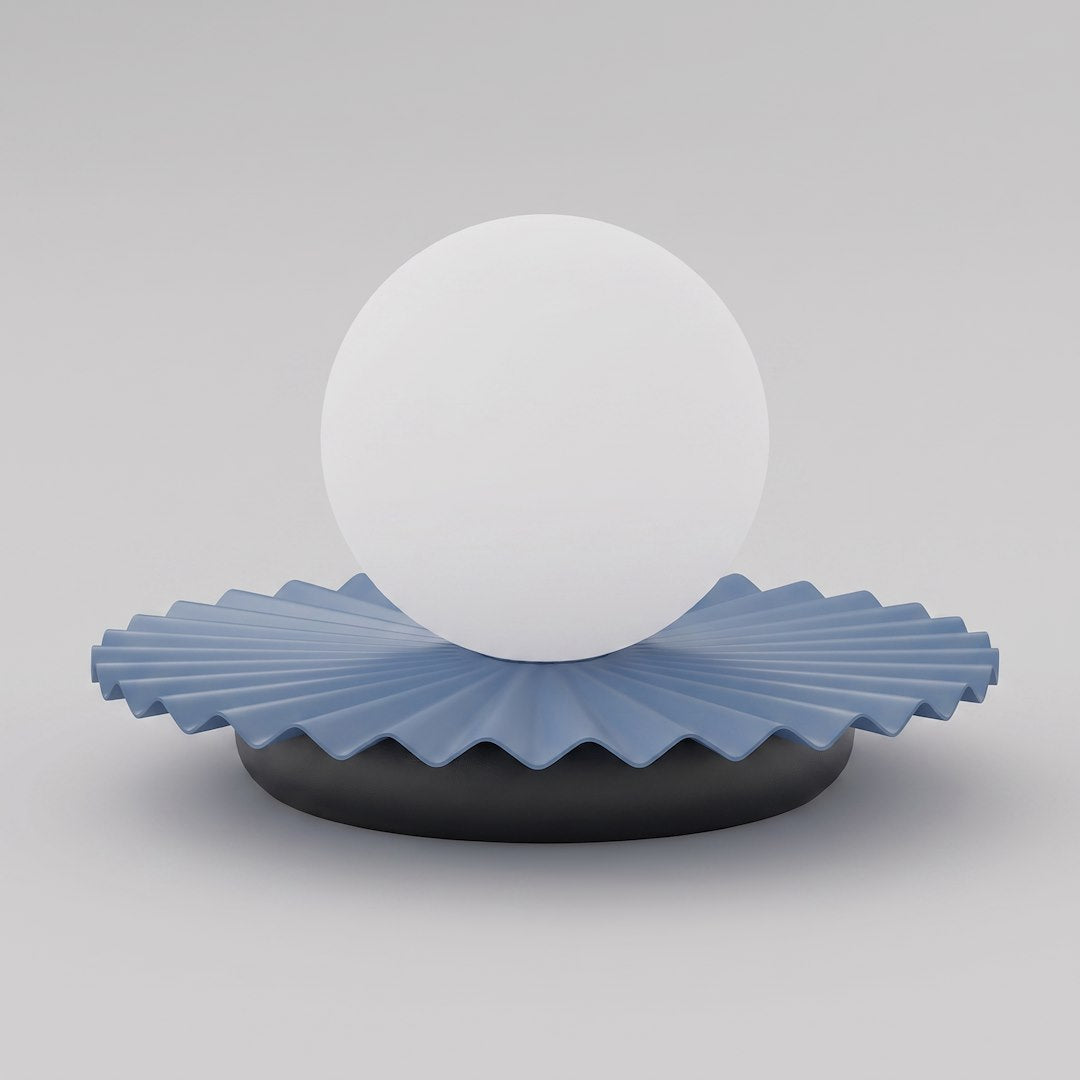 Lampe à poser de face, globe blanc laiteux sur socle plissé bleu.