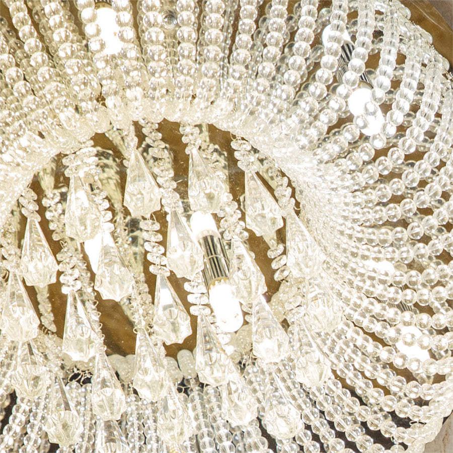 Gros plan sur les perles de verre et les ampoules allumées du luminaire.