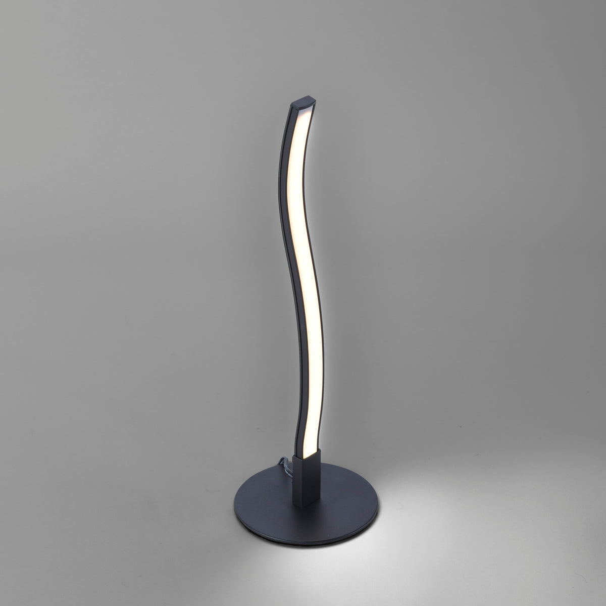 Autre angle sur fond gris, socle circulaire et tige ondulée noire allumée.