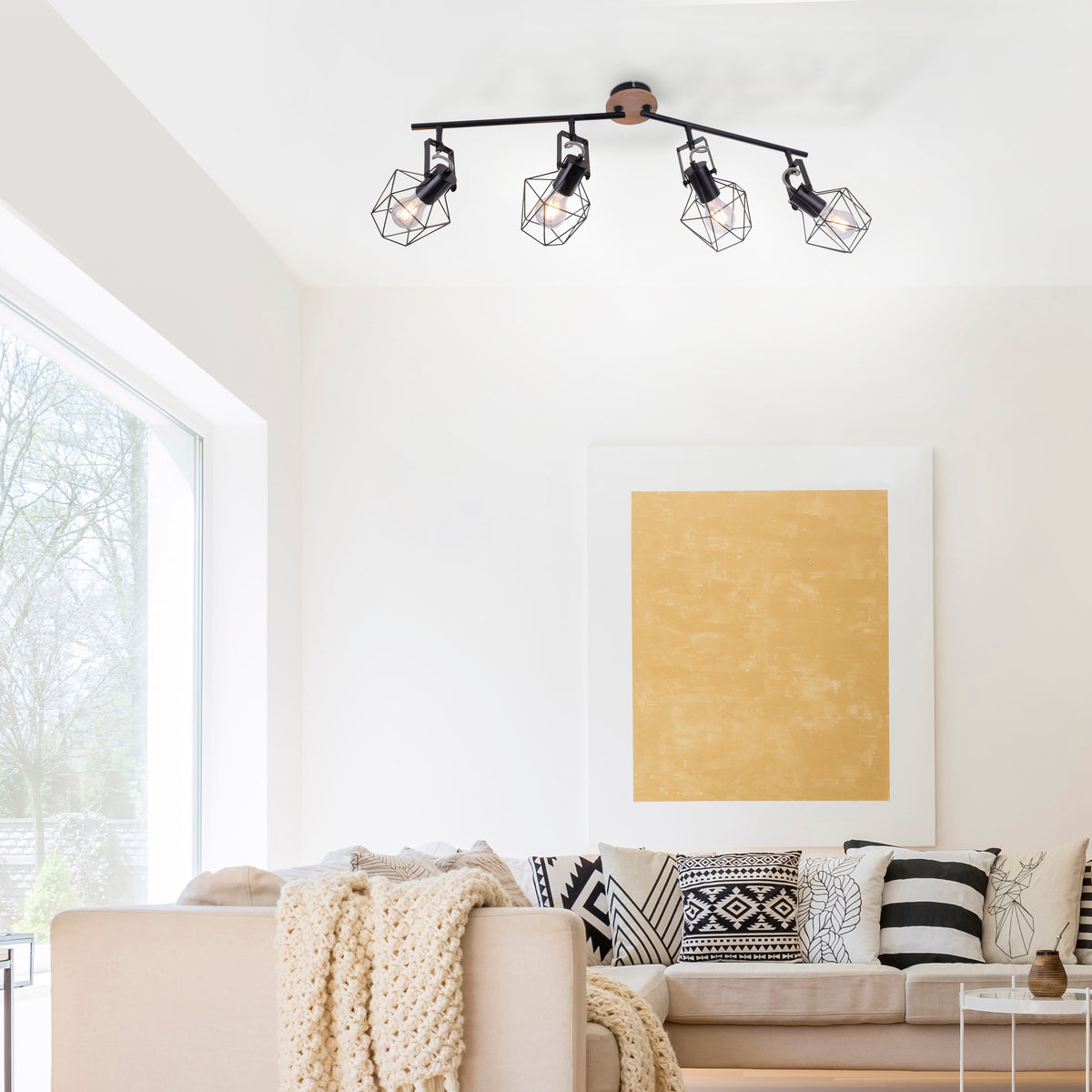 Mise en ambiance dans un salon clair, plafonnier allumé au-dessus du canapé beige.