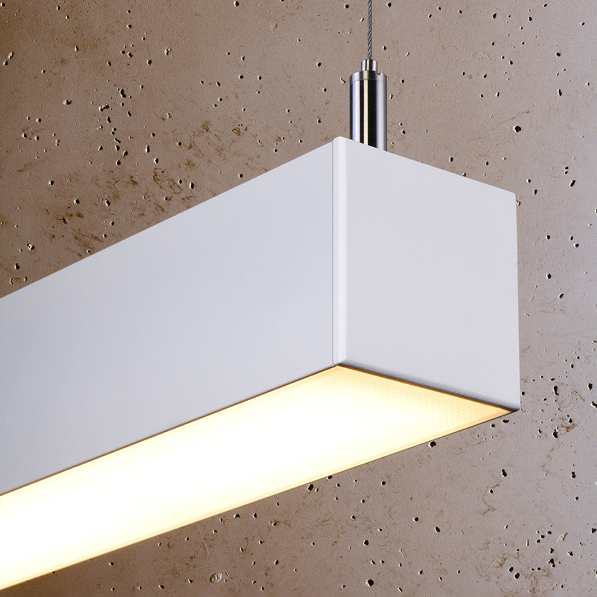 Détail de l'angle du luminaire allumé, diffuseur diffusant une lumière chaude