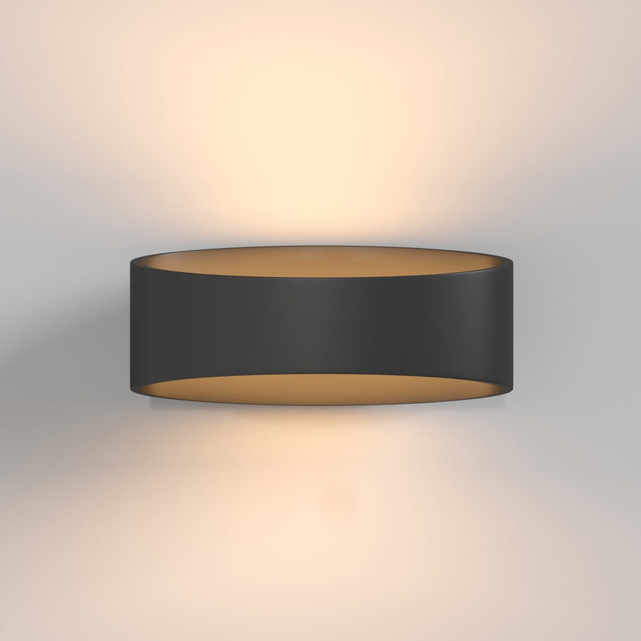 Luminaire allumé fixé au mur diffusant une lumière chaude vers le haut et le bas