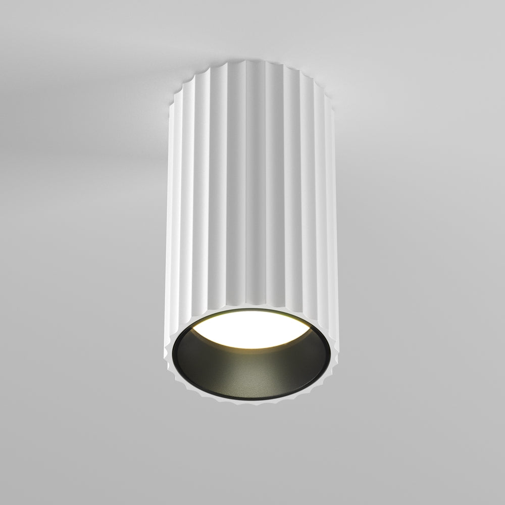 Plafonnier blanc cylindrique à surface cannelée, vu de face sous le plafond.
