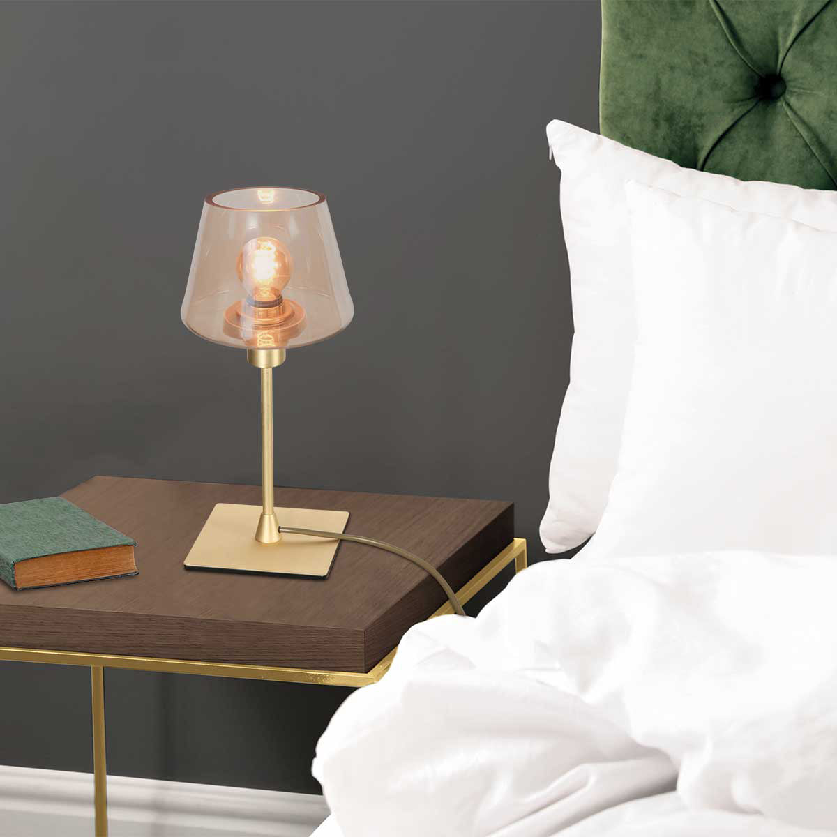 Mise en ambiance : lampe allumée sur une table de nuit en bois près d'un lit.