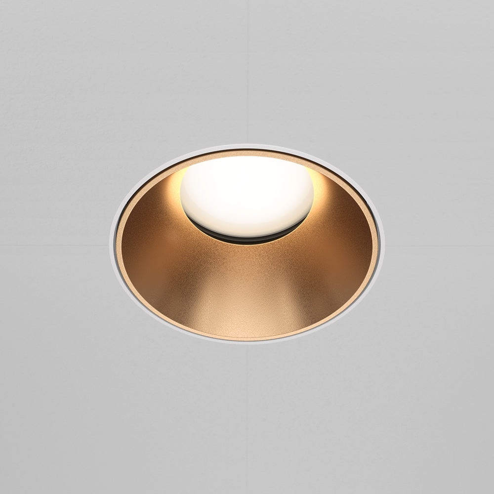 Vue de face du spot allumé diffusant une lumière douce sur le plafond blanc.