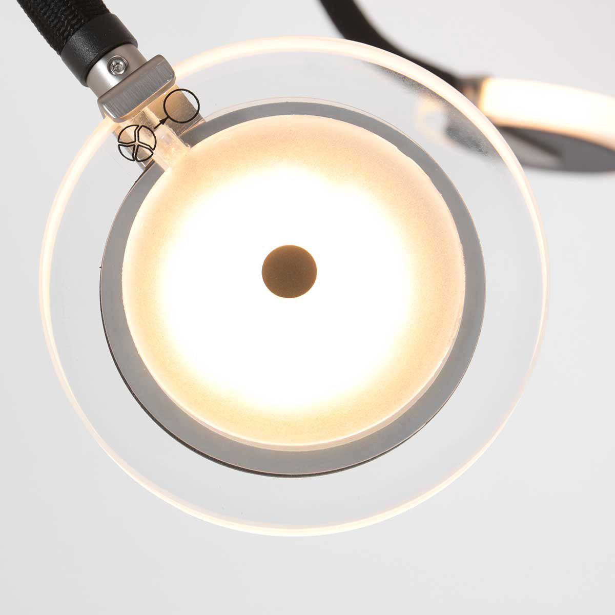 Gros plan sur un disque de verre lumineux avec cerclage métallique et trou central.