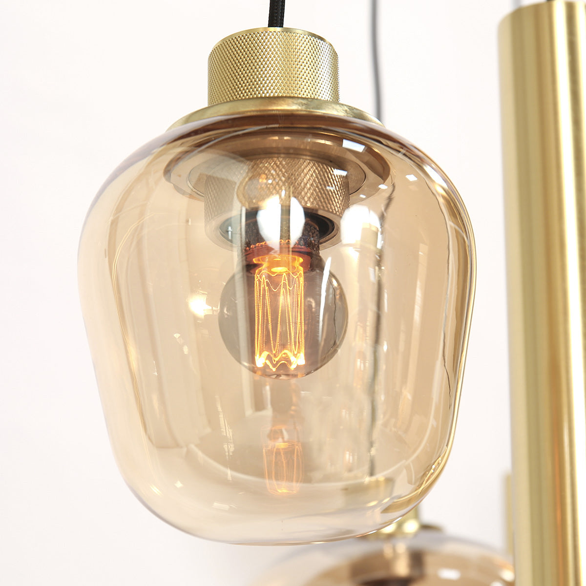 Gros plan d'un globe en verre ambré et de sa douille laiton avec ampoule à filament