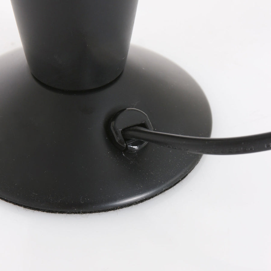 Détail de la base ronde noire avec le passage du cordon et une bande antidérapante.