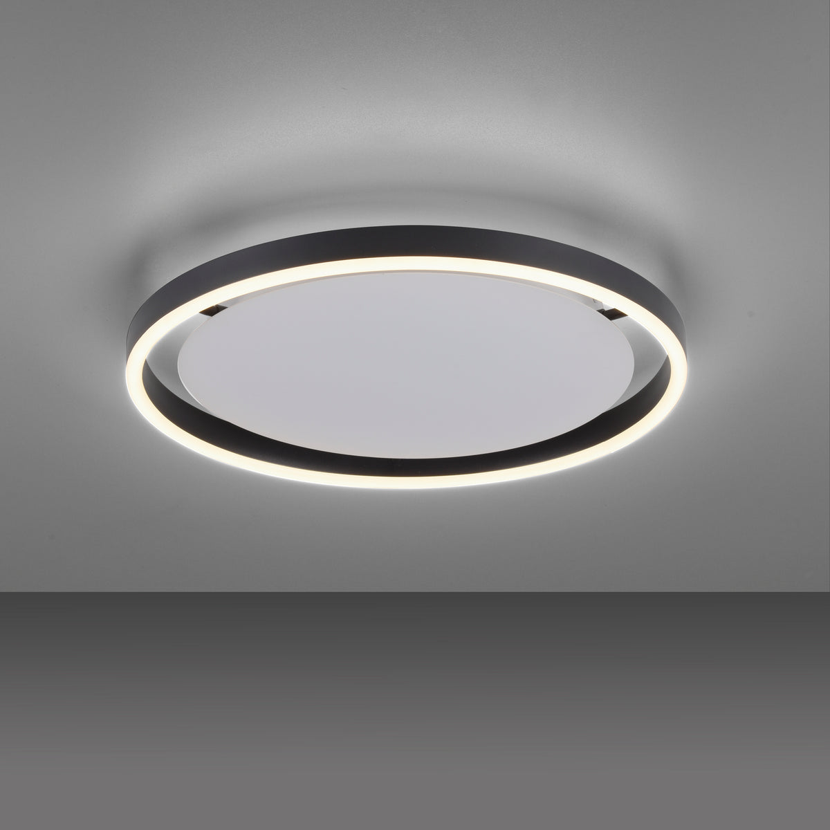Plafonnier allumé vu de dessous sur plafond gris, halo de lumière diffusé