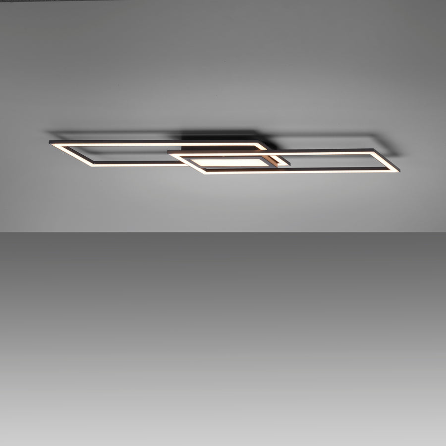Plafonnier noir allumé au plafond, diffusant une lumière blanche chaude dans une pièce sombre.