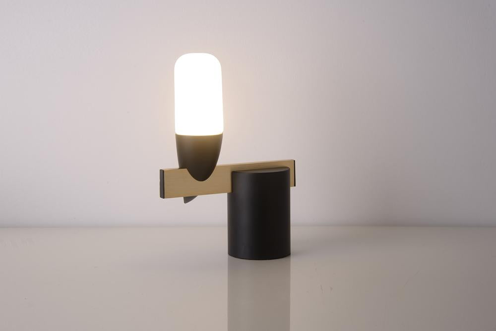Vue de face du luminaire allumé, abat-jour blanc et base cylindrique noire