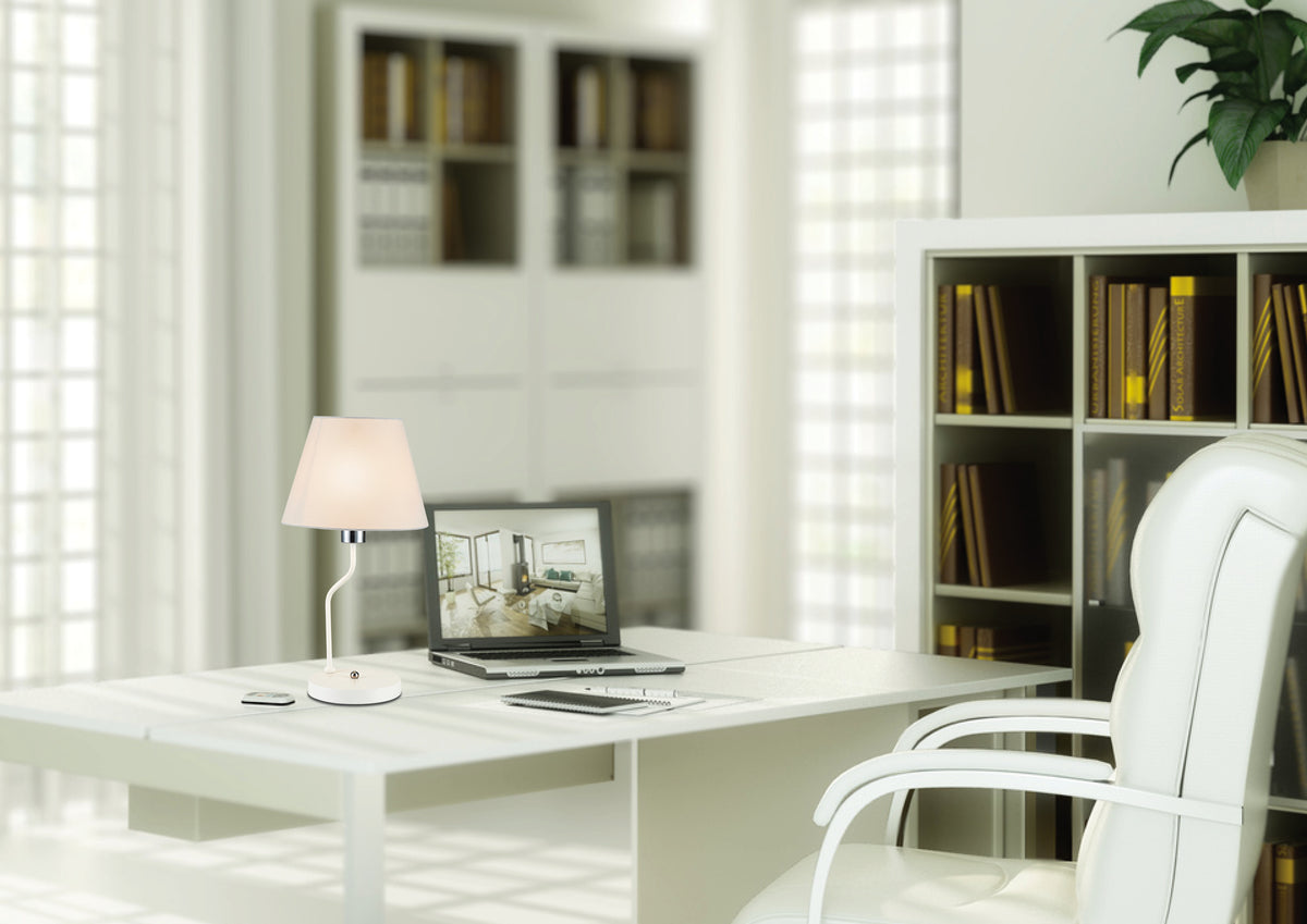 Lampe à poser blanche allumée près d'un ordinateur, intérieur de bureau clair