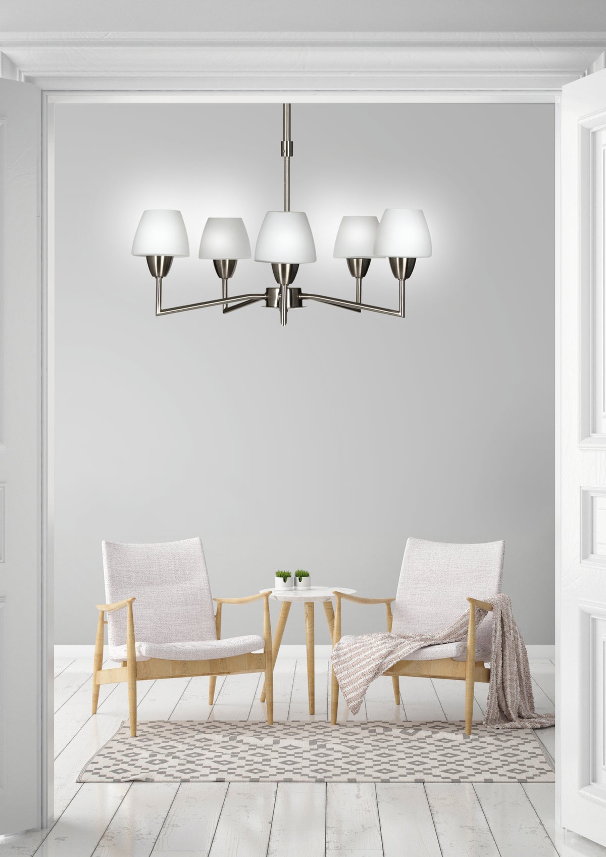 Mise en ambiance du luminaire suspendu au-dessus d'un salon blanc avec fauteuils en bois clair