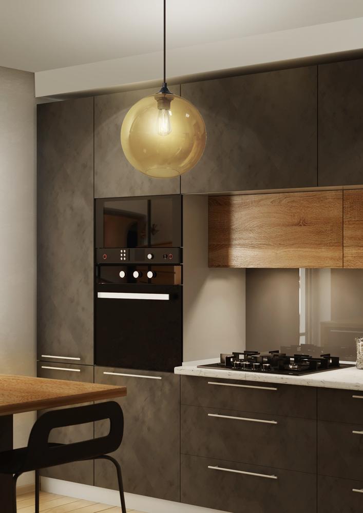 Suspension en verre ambré allumée dans une cuisine moderne aux meubles sombres et bois.