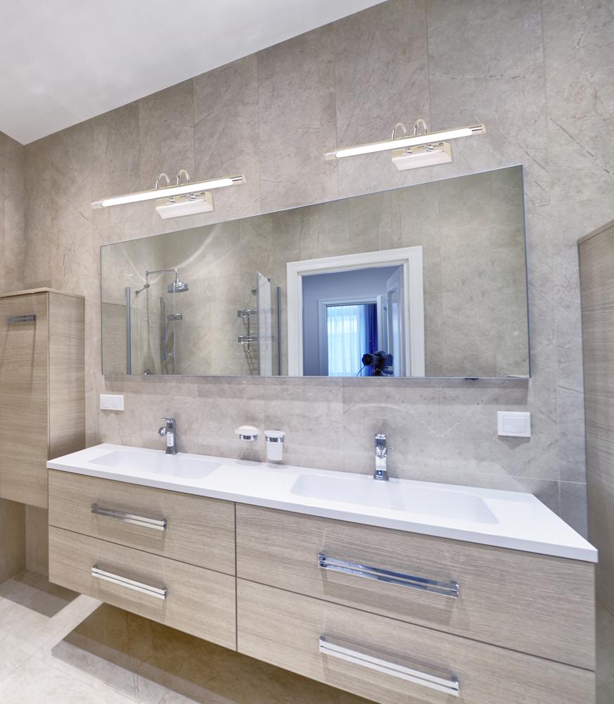 Vue légèrement différente de la même salle de bain, appliques allumées au-dessus du miroir.