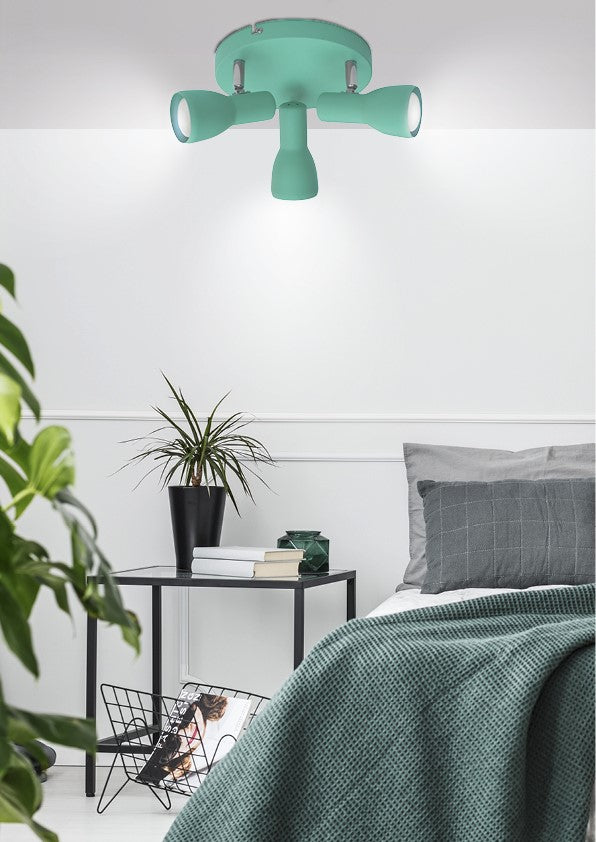 Mise en ambiance du plafonnier turquoise dans une chambre avec lit et plante.