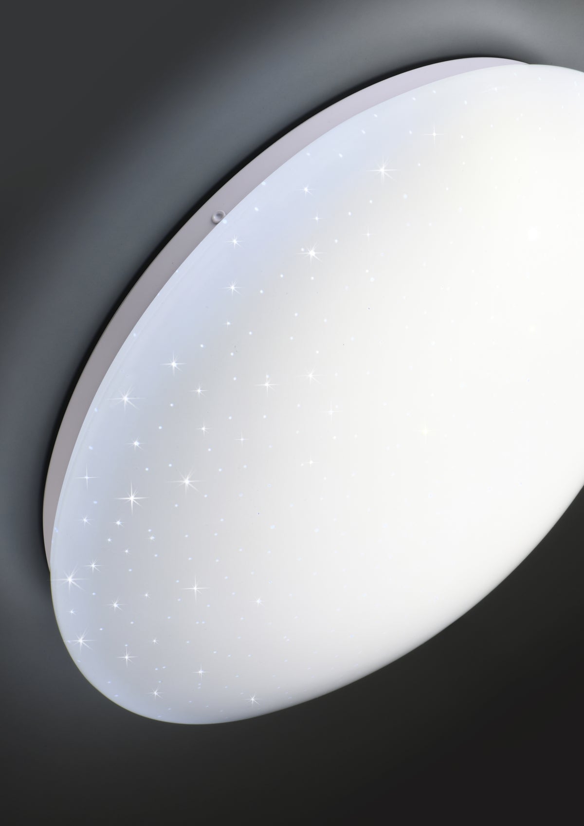 Détail rapproché du plafonnier allumé montrant le bord blanc et le ciel étoilé