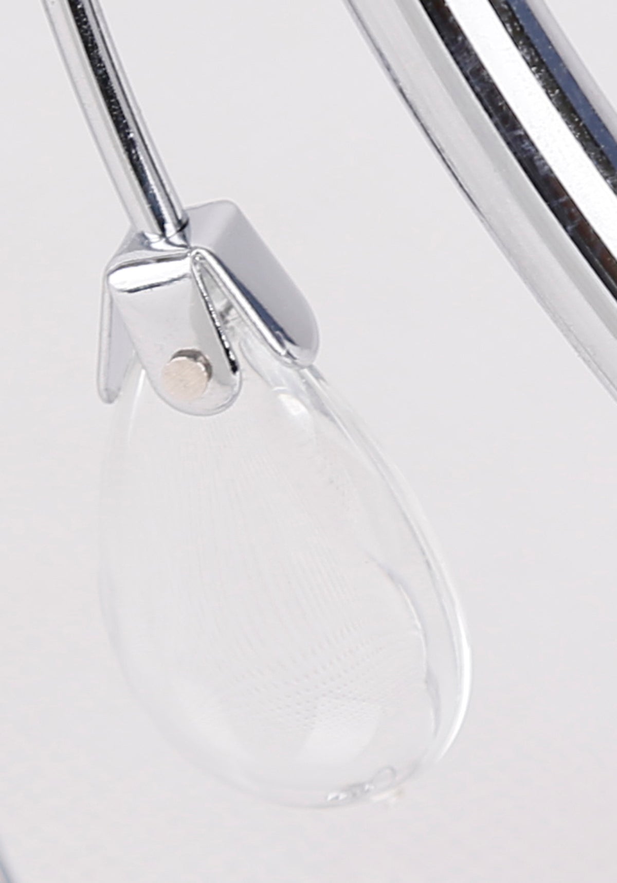 Détail d'une goutte en verre transparent suspendue à une armature chromée