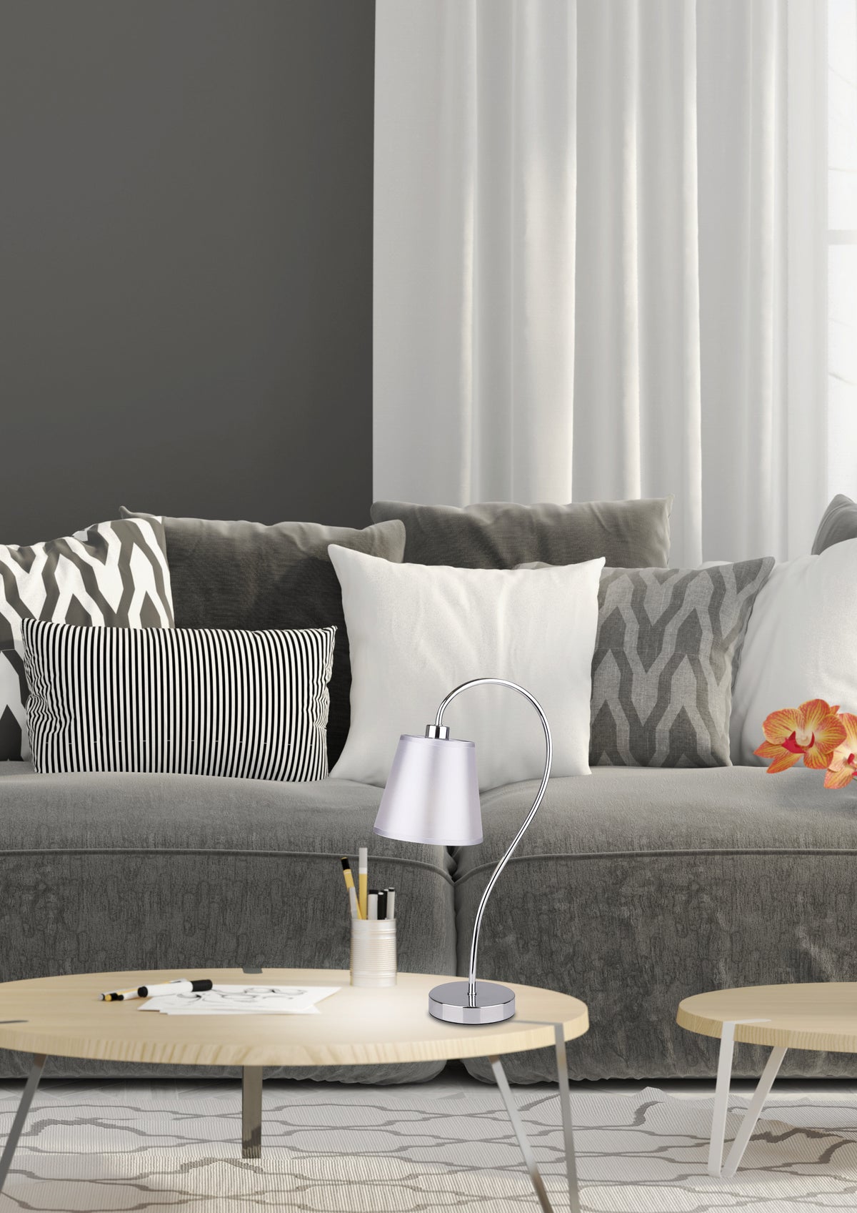 Lampe posée sur table basse, canapé gris et coussins en arrière-plan.