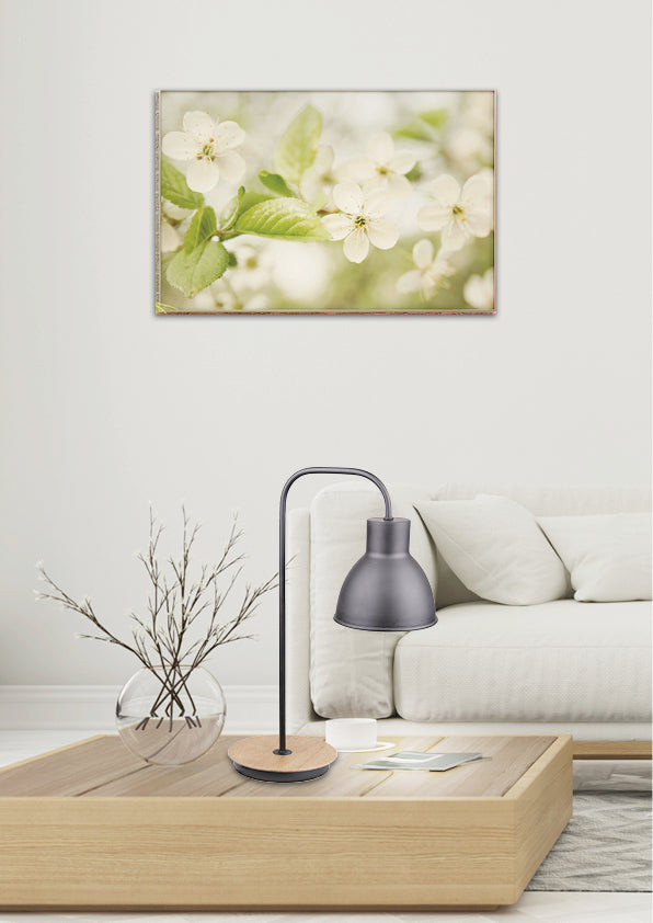 Mise en ambiance salon : lampe posée sur table basse, canapé blanc et cadre floral au mur.