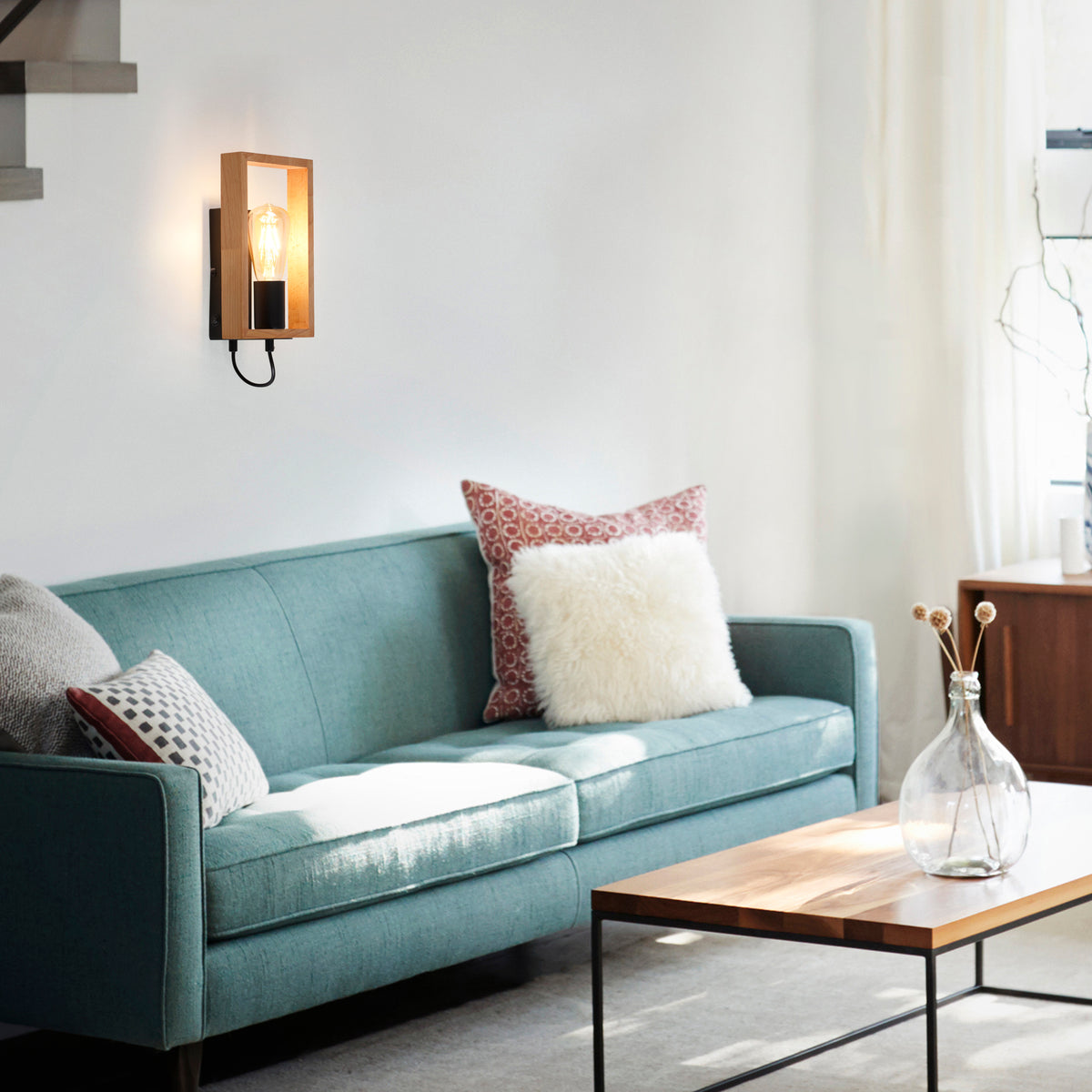 Mise en ambiance dans un salon, applique allumée au-dessus d'un canapé bleu.