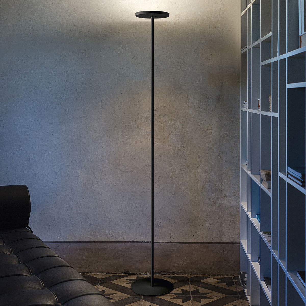 Lampadaire LED noir éclairant vers le haut dans un salon béton