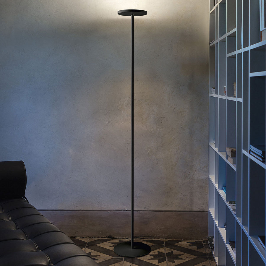Lampadaire LED noir éclairant vers le haut dans un salon béton