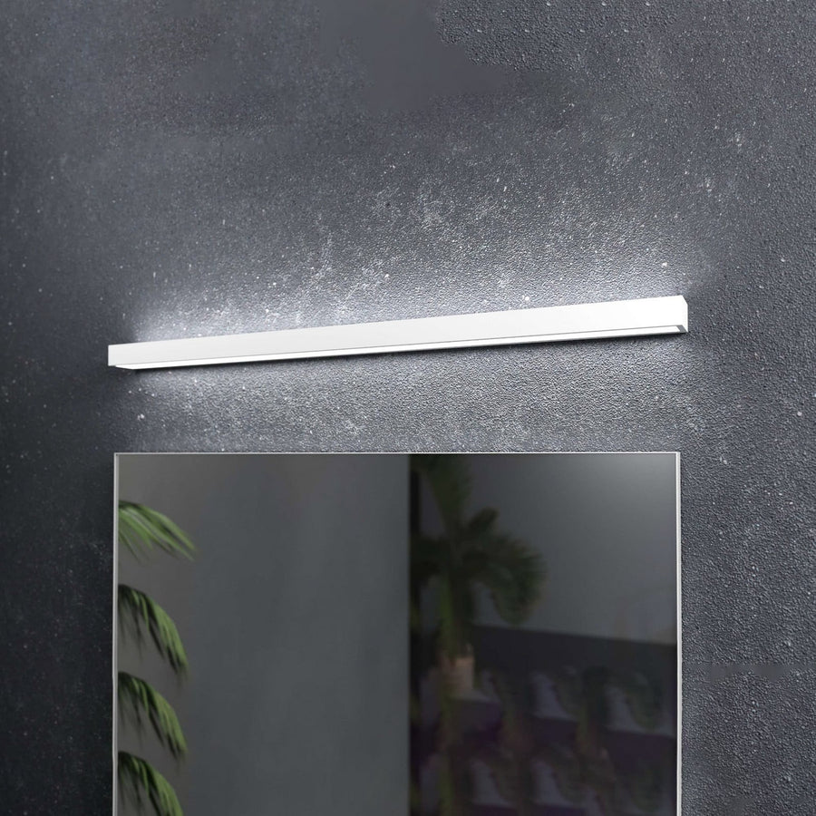 Vue de face de l'applique blanche au-dessus d'un miroir, sur mur sombre.
