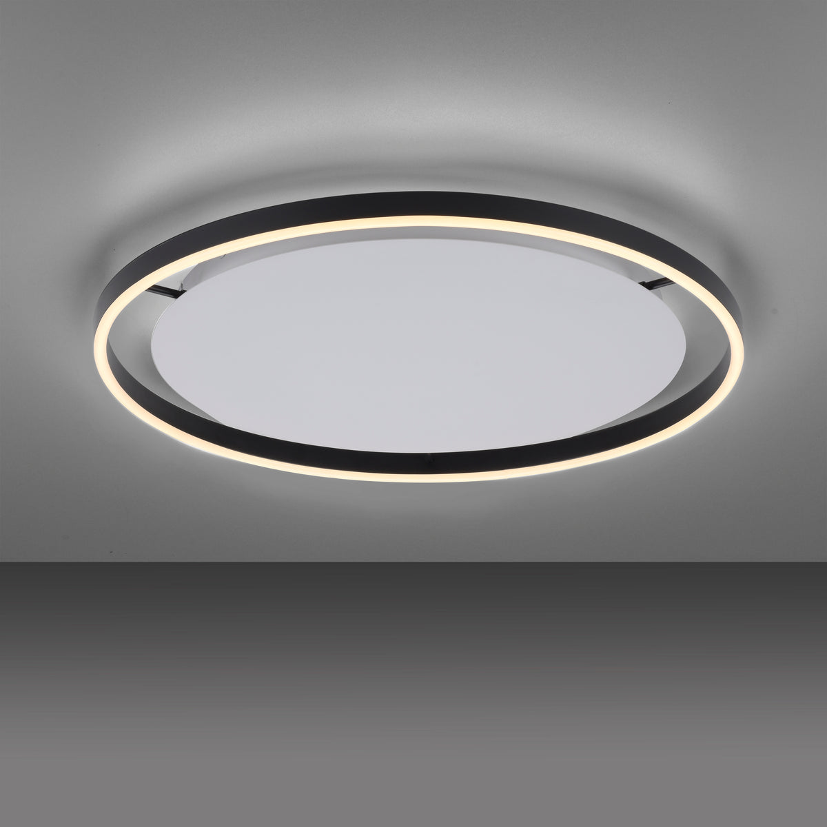 Plafonnier installé au plafond, anneau noir et halo lumineux blanc sur fond gris.