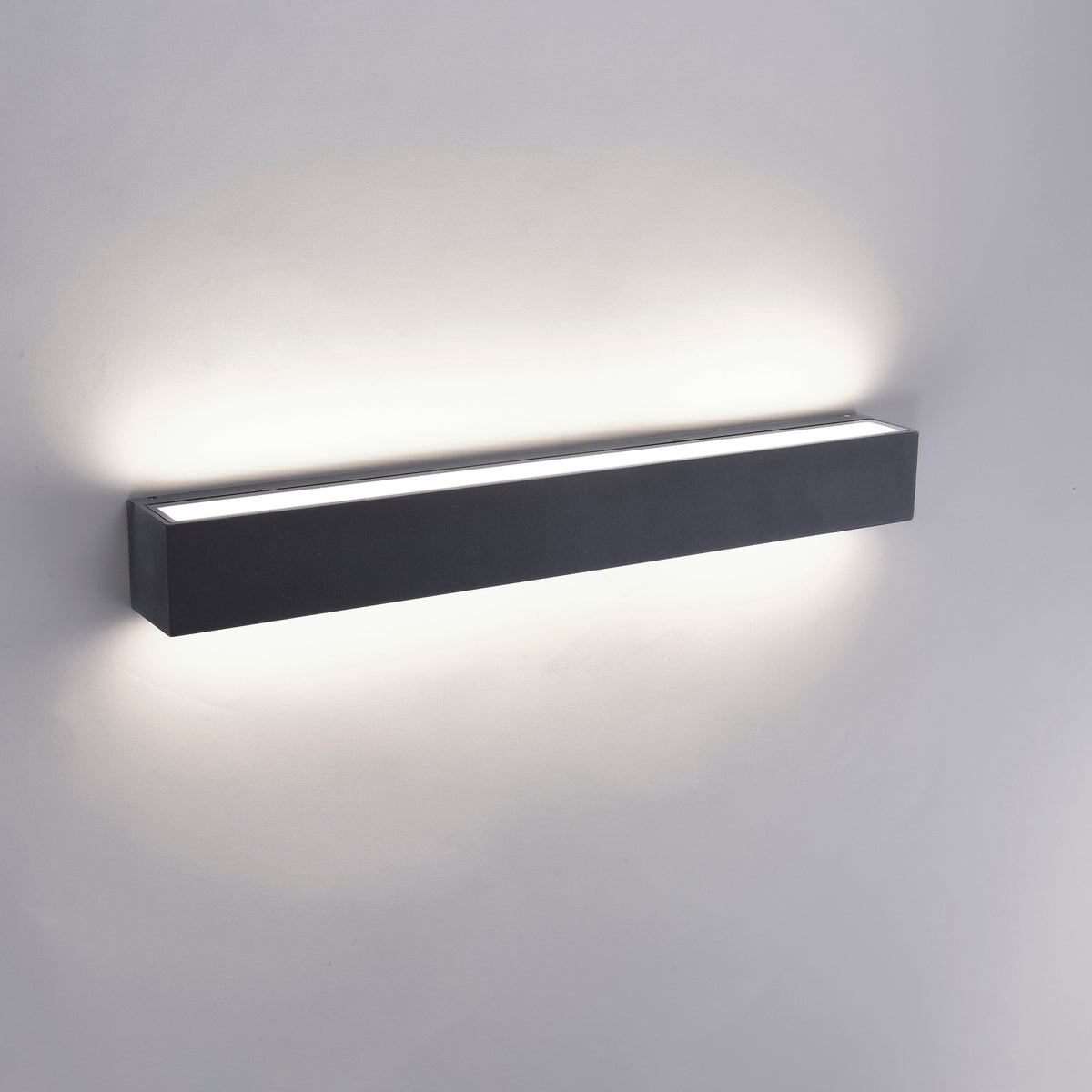Applique allumée sur mur blanc diffusant un halo de lumière chaude