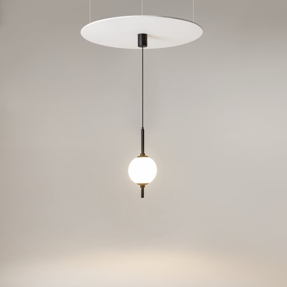 Suspension allumée sous un grand disque blanc, ambiance douce et minimaliste.