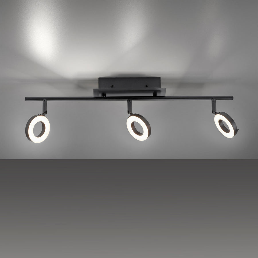 Plafonnier noir installé au plafond, trois anneaux LED diffusant une lumière chaude