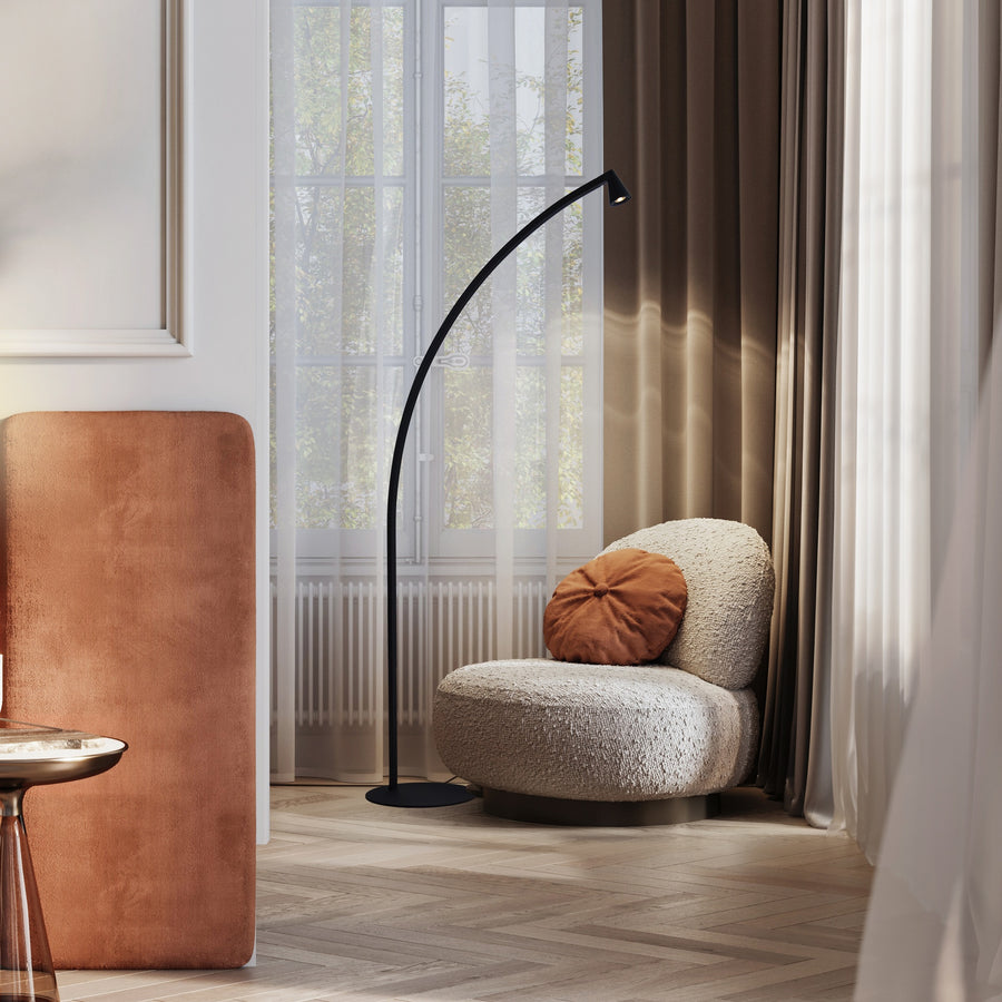 Lampadaire arqué noir installé près d'une fenêtre dans un salon contemporain avec fauteuil bouclé