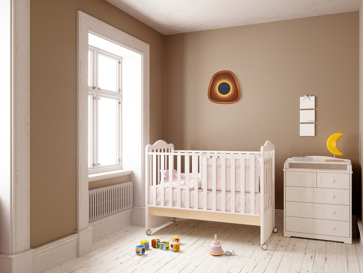 Mise en ambiance chambre d'enfant, applique murale cuivrée allumée sur mur beige.