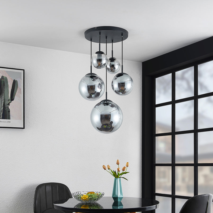 Les mêmes globes fumés pendent devant une grande fenêtre noire, au-dessus d'une table.