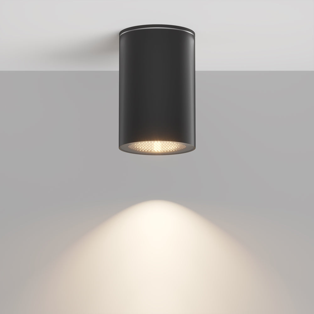 Luminaire cylindrique noir fixé au plafond, halo lumineux projeté vers le bas