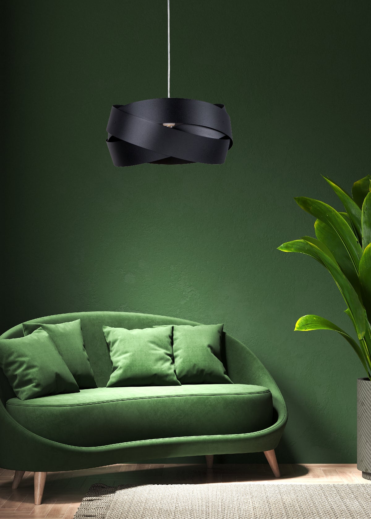 Ambiance salon vert, suspension noire au-dessus d'un canapé courbe et tapis