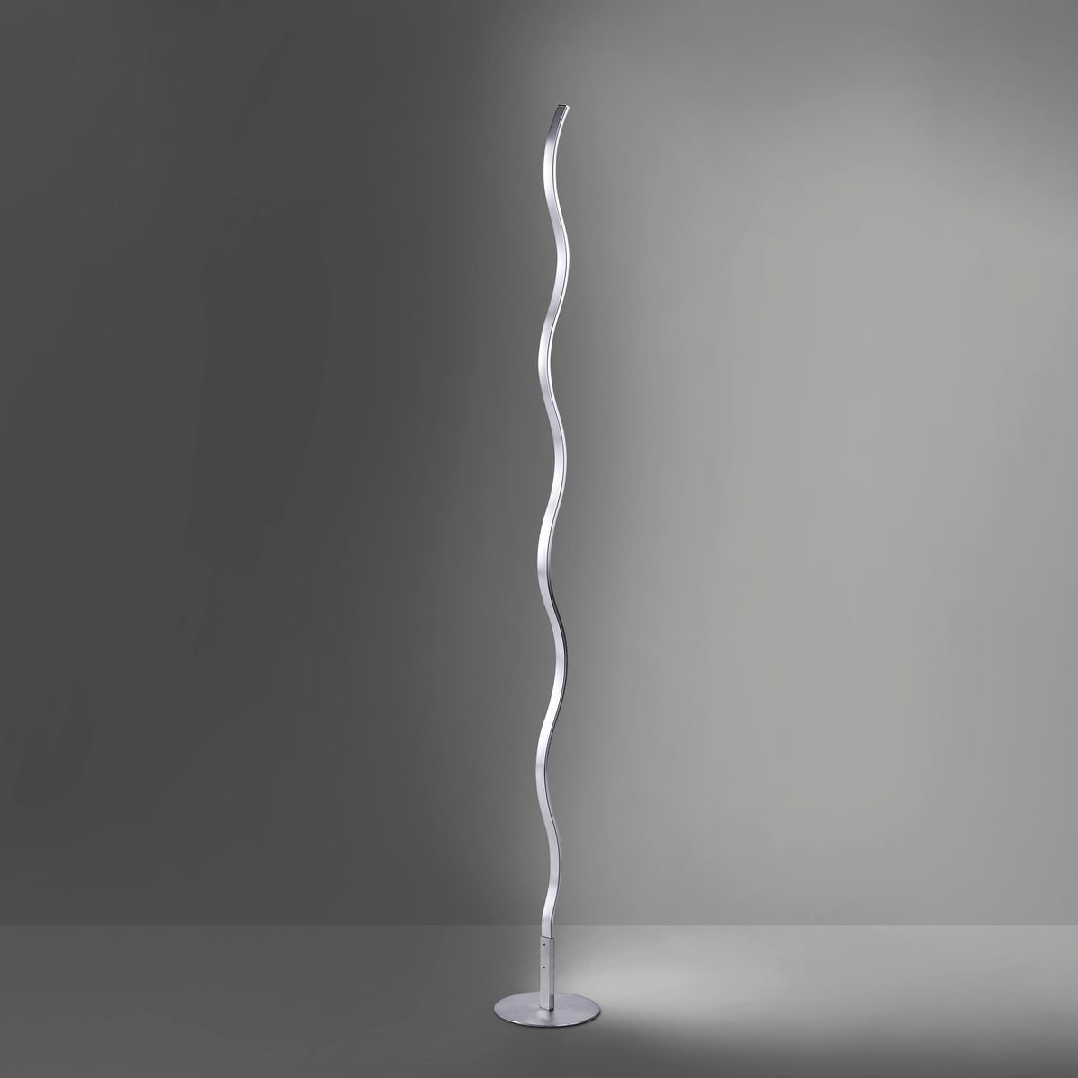 Lampadaire métallique allumé dans une pièce sombre, halo de lumière diffuse au sol.