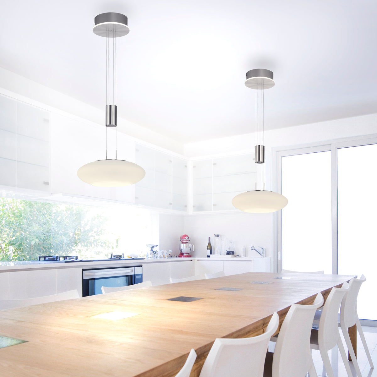Deux suspensions allumées au-dessus d'un îlot de cuisine blanc avec table en bois