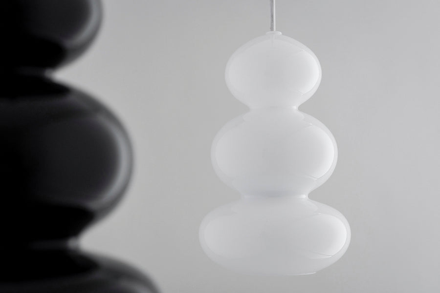 Gros plan sur une suspension blanche, une autre suspension noire floue en arrière-plan.