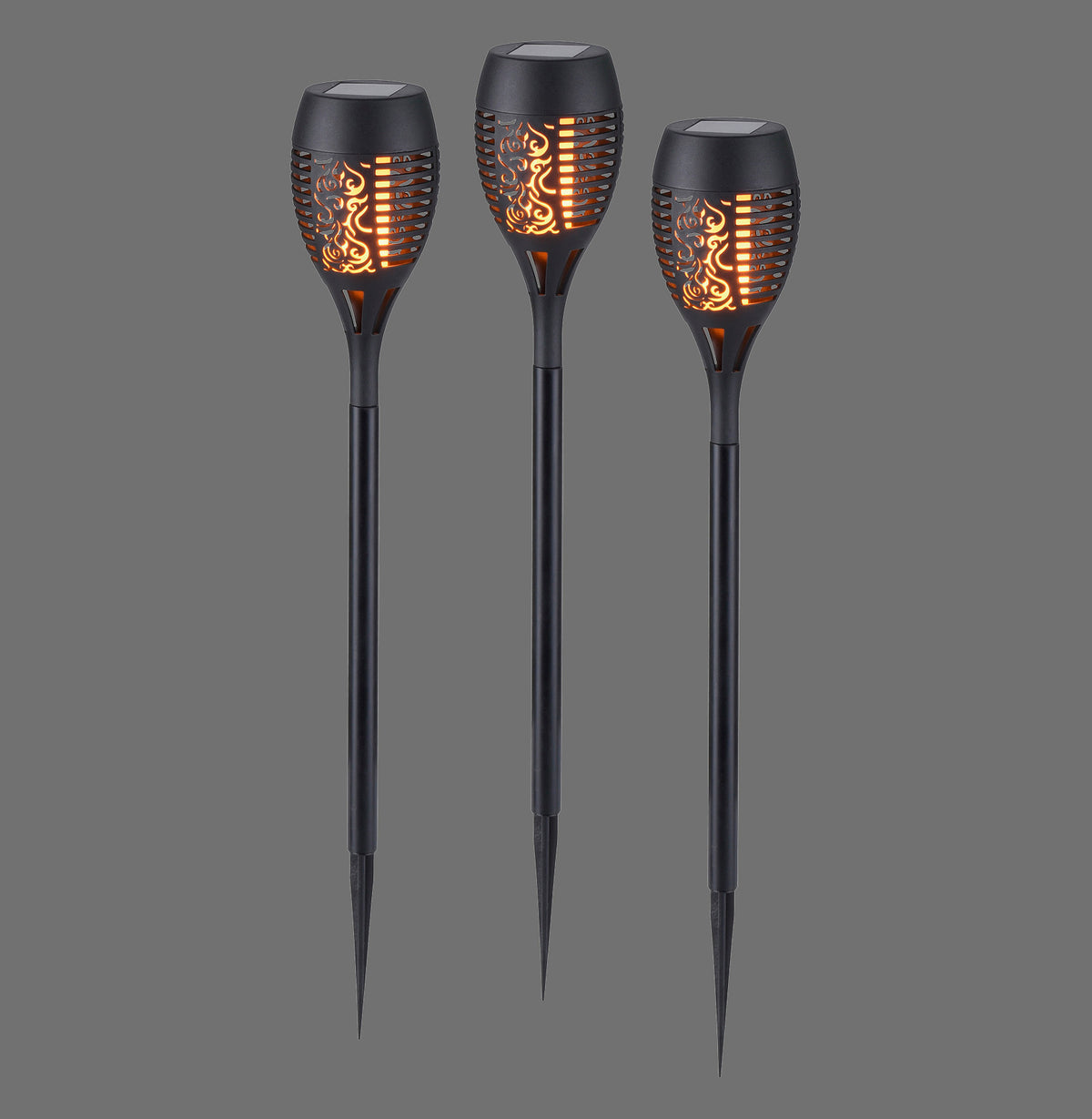 Trois piquets lumineux solaires noirs avec effet flamme allumé sur fond gris.